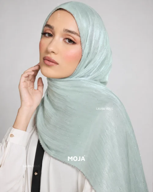 Woman wearing pastel green Moja organza shimmer hijab, silver chain lace border, draped instant style